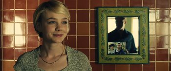 Movie still from “Drive” (2011), directed by Nicolas Winding Refn – A woman standing in front of a picture of a family; Close Up shot, Over the shoulder angle