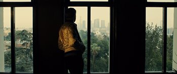 Movie still from “Drive” (2011), directed by Nicolas Winding Refn – A man standing in front of a window looking out at a city skyline; Wide shot, High angle