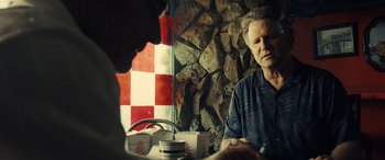 Movie still from “Drive” (2011), directed by Nicolas Winding Refn – A man sitting in front of a brick wall; Close Up shot, Over the shoulder angle