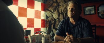 Movie still from “Drive” (2011), directed by Nicolas Winding Refn – An older man sitting at a table in front of a brick wall; Close Up shot, Low angle