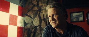 Movie still from “Drive” (2011), directed by Nicolas Winding Refn – An older man sitting in front of a stone wall; Close Up shot, Low angle