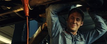 Movie still from “Drive” (2011), directed by Nicolas Winding Refn – A man is holding a piece of wood up to the ceiling; Close Up shot, Over the shoulder angle