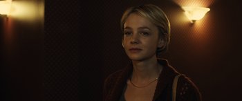 Movie still from “Drive” (2011), directed by Nicolas Winding Refn – A woman with short blonde hair wearing a brown jacket; Close Up shot, Over the shoulder angle