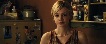 Movie still from “Drive” (2011), directed by Nicolas Winding Refn – A woman with short blonde hair wearing a red and gold top; Close Up shot, Over the shoulder angle