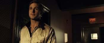 Movie still from “Drive” (2011), directed by Nicolas Winding Refn – A man standing in a room in front of a window; Close Up shot, Over the shoulder angle