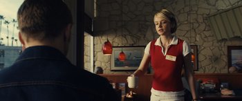 Movie still from “Drive” (2011), directed by Nicolas Winding Refn – A woman in a red shirt is holding a white cup; Medium shot, Over the shoulder angle