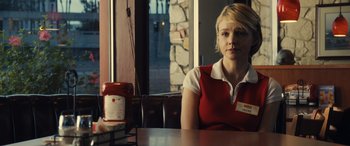 Movie still from “Drive” (2011), directed by Nicolas Winding Refn – A woman sitting at a table in front of a jar; Medium shot, Over the shoulder angle