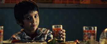 Movie still from “Drive” (2011), directed by Nicolas Winding Refn – A young boy holding a glass of orange juice; Close Up shot, Over the shoulder angle