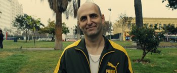 Movie still from “Drive” (2011), directed by Nicolas Winding Refn – A bald man in a yellow and black jacket; Close Up shot, Over the shoulder angle