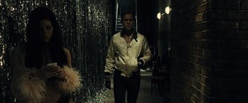 Movie still from “Drive” (2011), directed by Nicolas Winding Refn – A man in a white jacket walking in a dark room; Medium shot, Over the shoulder angle