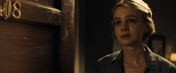 Movie still from “Drive” (2011), directed by Nicolas Winding Refn – A young woman in a jacket standing next to a wall; Close Up shot, Over the shoulder angle