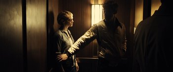 Movie still from “Drive” (2011), directed by Nicolas Winding Refn – A man and a woman standing next to each other in front of a window; Medium shot, Low angle