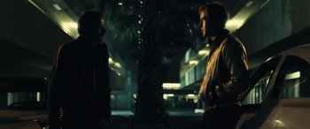 Movie still from “Drive” (2011), directed by Nicolas Winding Refn – Two people standing in the dark near a palm tree at night; Medium shot, Over the shoulder angle