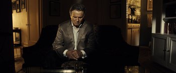 Movie still from “Drive” (2011), directed by Nicolas Winding Refn – A man sitting in a chair with his hands clasped together; Medium shot, High angle