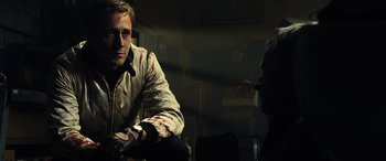 Movie still from “Drive” (2011), directed by Nicolas Winding Refn – A man with a bandaged arm sitting next to another man; Close Up shot, Over the shoulder angle