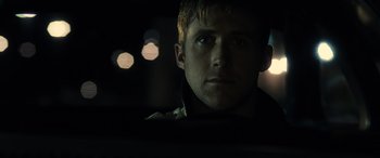 Movie still from “Drive” (2011), directed by Nicolas Winding Refn – A person in a car at night; Close Up shot, Over the shoulder angle