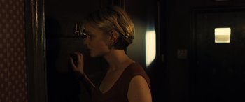 Movie still from “Drive” (2011), directed by Nicolas Winding Refn – A woman standing next to a wall in a dark room; Close Up shot, Over the shoulder angle