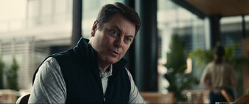 Movie still from “Dumb Money” (2023), directed by Craig Gillespie – A person sitting in a chair; Close Up shot, Over the shoulder angle