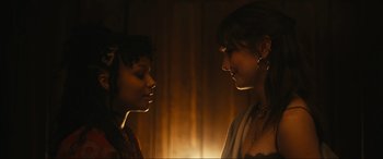 Movie still from “Dumb Money” (2023), directed by Craig Gillespie – Two women standing next to each other in front of a light; Close Up shot, Over the shoulder angle