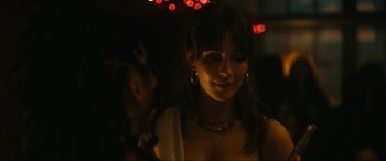 Movie still from “Dumb Money” (2023), directed by Craig Gillespie – A woman is smiling at the camera in the dark; Close Up shot, Over the shoulder angle