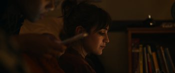 Movie still from “Dumb Money” (2023), directed by Craig Gillespie – A woman with ear buds in her ears; Close Up shot, Over the shoulder angle