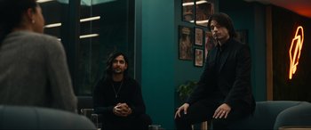 Movie still from “Dumb Money” (2023), directed by Craig Gillespie – Two men sitting next to each other in front of a window; Medium shot, Over the shoulder angle