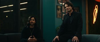 Movie still from “Dumb Money” (2023), directed by Craig Gillespie – Two men are sitting in a room and one of them is holding a cell phone in his hand; Medium shot, Over the shoulder angle