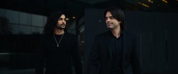 Movie still from “Dumb Money” (2023), directed by Craig Gillespie – Two men in black suits are standing next to each other; Medium shot, Low angle