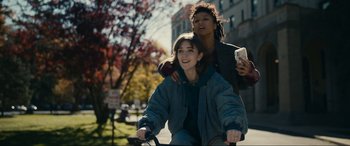 Movie still from “Dumb Money” (2023), directed by Craig Gillespie – Two people on a bike on a street; Medium shot, Low angle
