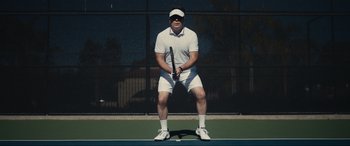 Movie still from “Dumb Money” (2023), directed by Craig Gillespie – A man holding a tennis racquet on top of a tennis court; Medium shot, Low angle