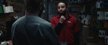 Movie still from “Dumb Money” (2023), directed by Craig Gillespie – A man in a red shirt standing in front of a mirror; Close Up shot, Over the shoulder angle