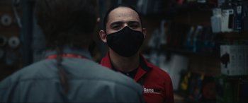 Movie still from “Dumb Money” (2023), directed by Craig Gillespie – A man wearing a black face mask standing next to another man wearing a red shirt; Close Up shot, Over the shoulder angle