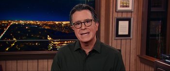 Movie still from “Dumb Money” (2023), directed by Craig Gillespie – A person wearing glasses and a green shirt; Medium shot, Over the shoulder angle