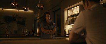 Movie still from “Dumb Money” (2023), directed by Craig Gillespie – A woman standing in front of a mirror in a room; Medium shot, Over the shoulder angle