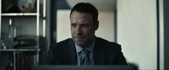 Movie still from “Dumb Money” (2023), directed by Craig Gillespie – A person wearing a suit and tie; Close Up shot, Over the shoulder angle