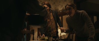 Movie still from “Dumb Money” (2023), directed by Craig Gillespie – A man and a woman standing at a table with a plate of food; Medium shot, Over the shoulder angle