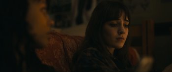 Movie still from “Dumb Money” (2023), directed by Craig Gillespie – A woman sitting on top of a couch in a living room; Close Up shot, Over the shoulder angle