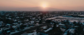 Movie still from “Dumb Money” (2023), directed by Craig Gillespie – An aerial view of the sun setting over a neighborhood; Extreme Wide shot, Low angle