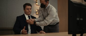 Movie still from “Dumb Money” (2023), directed by Craig Gillespie – A man is helping another man put on a tie; Medium shot, Over the shoulder angle