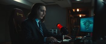 Movie still from “Dumb Money” (2023), directed by Craig Gillespie – A man sitting at a desk with a microphone; Medium shot, Low angle