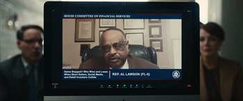 Movie still from “Dumb Money” (2023), directed by Craig Gillespie – A television screen showing a man in a suit and tie; Close Up shot, High angle