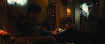 Movie still from “Dumb Money” (2023), directed by Craig Gillespie – A man sitting on a couch while using a cell phone; Medium shot, Low angle