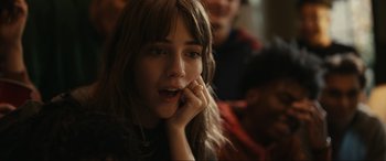 Movie still from “Dumb Money” (2023), directed by Craig Gillespie – A woman with a surprised look on her face; Close Up shot, Over the shoulder angle