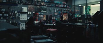 Movie still from “Dumb Money” (2023), directed by Craig Gillespie – A man sitting in front of a computer in a store; Wide shot, Over the shoulder angle