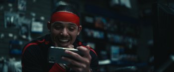 Movie still from “Dumb Money” (2023), directed by Craig Gillespie – A man with a red headband looking at a cell phone; Close Up shot, Low angle