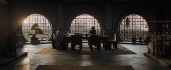 Movie still from “Dune” (2021), directed by Denis Villeneuve – Two people sitting at a table in front of a large window; Wide shot, High angle