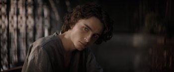 Movie still from “Dune” (2021), directed by Denis Villeneuve – A young man with long hair is looking at the camera; Close Up shot, Over the shoulder angle