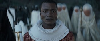 Movie still from “Dune” (2021), directed by Denis Villeneuve – A man wearing a red and white shirt and a white collar; Close Up shot, Over the shoulder angle