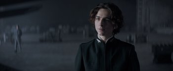 Movie still from “Dune” (2021), directed by Denis Villeneuve – A man in a black jacket is looking at the camera; Close Up shot, Low angle