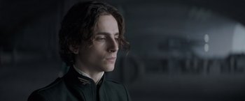 Movie still from “Dune” (2021), directed by Denis Villeneuve – A man with long dark hair wearing a black jacket; Close Up shot, Low angle